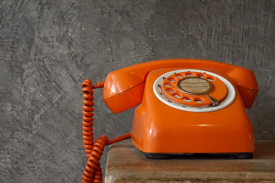 Orange phone on table with grey background. 