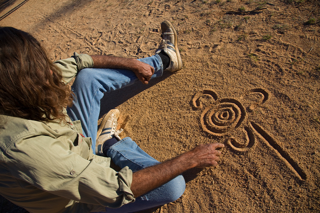 Person making art in sand. 